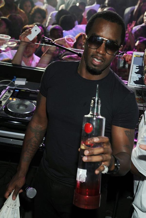 Sean Combs hosting a Black and White Attire Memorial Day Weekend Party in Las Vegas, holding a bottle, with Zeinab Badawi in attendance