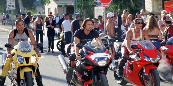 Three bikers in Torque lined up for a street race as a crowd gathers behind them