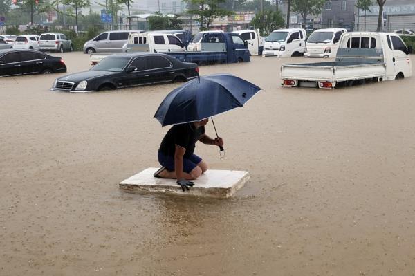 在全南木浦市石岘洞，工人们在被大雨淹没的街道上通勤，时间是周一早晨。